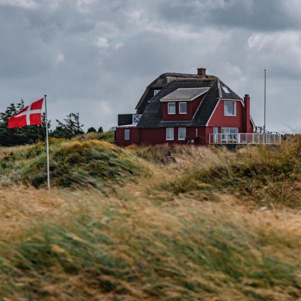 Rødt feriehus i grønne omgivelser ved Vejers