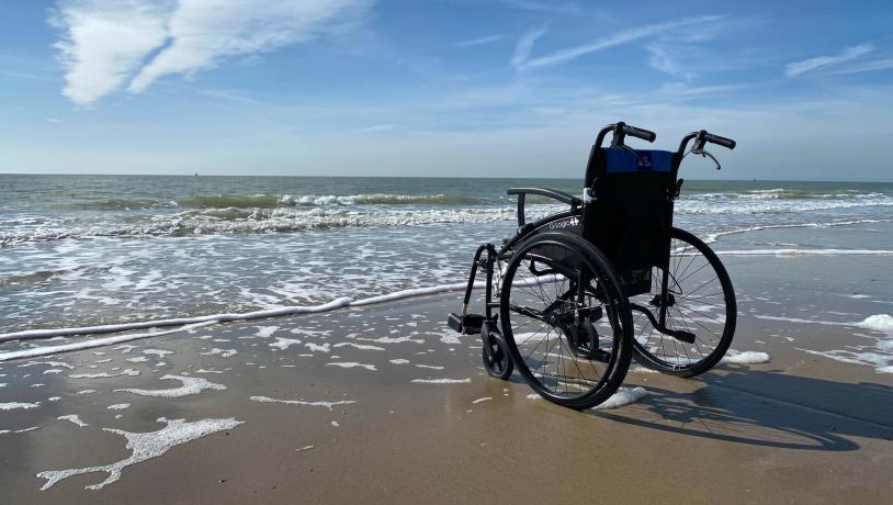 Kørestol på stranden i vandkanten