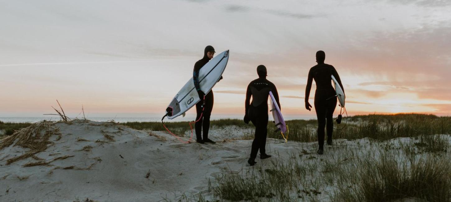 Surfers on a dune in sunset by the North Sea