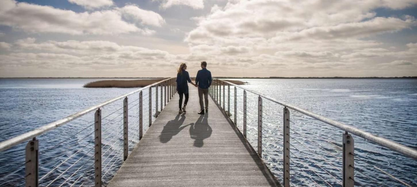 Et par som går ved vesterhavet på en bro på en smuttur