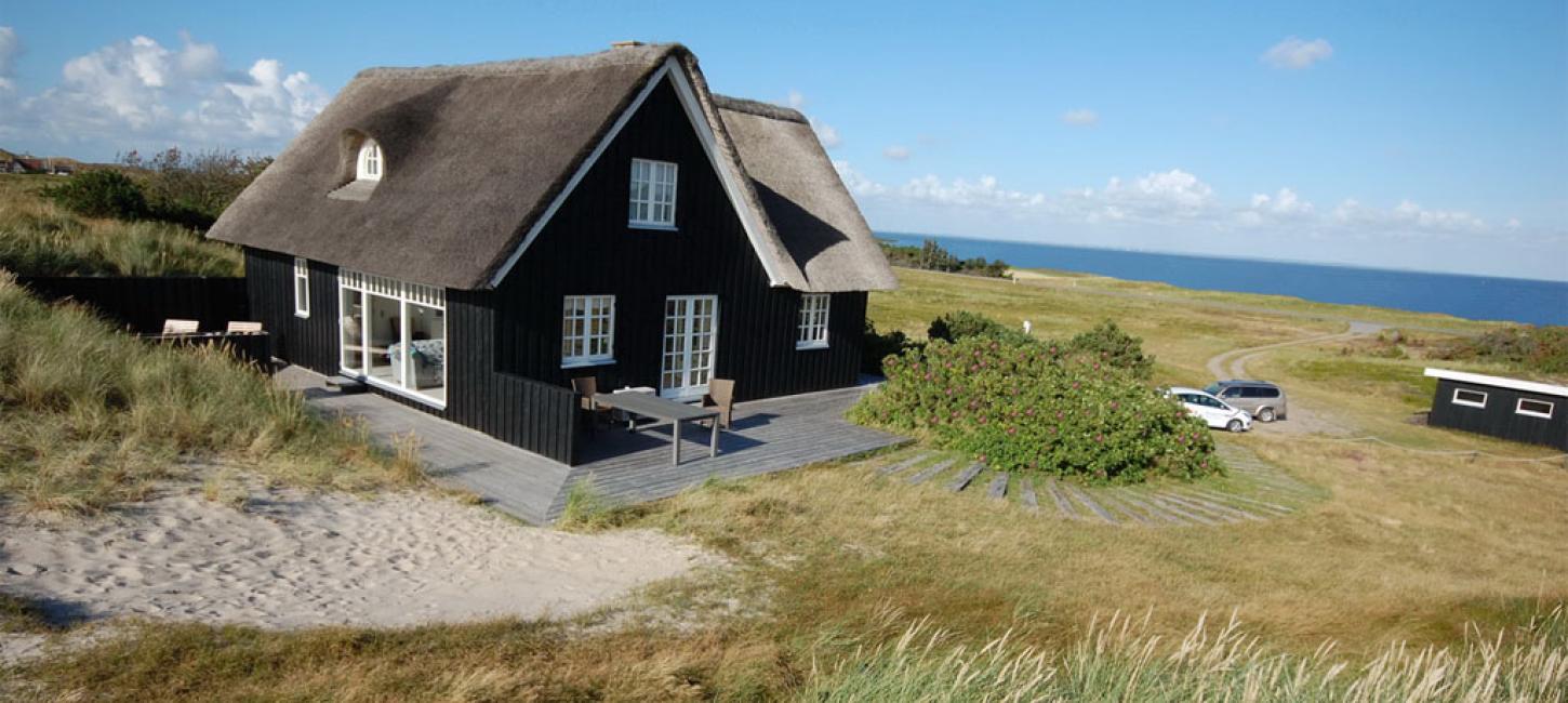 Sort feriehus med stråtag tæt på Vesterhavet