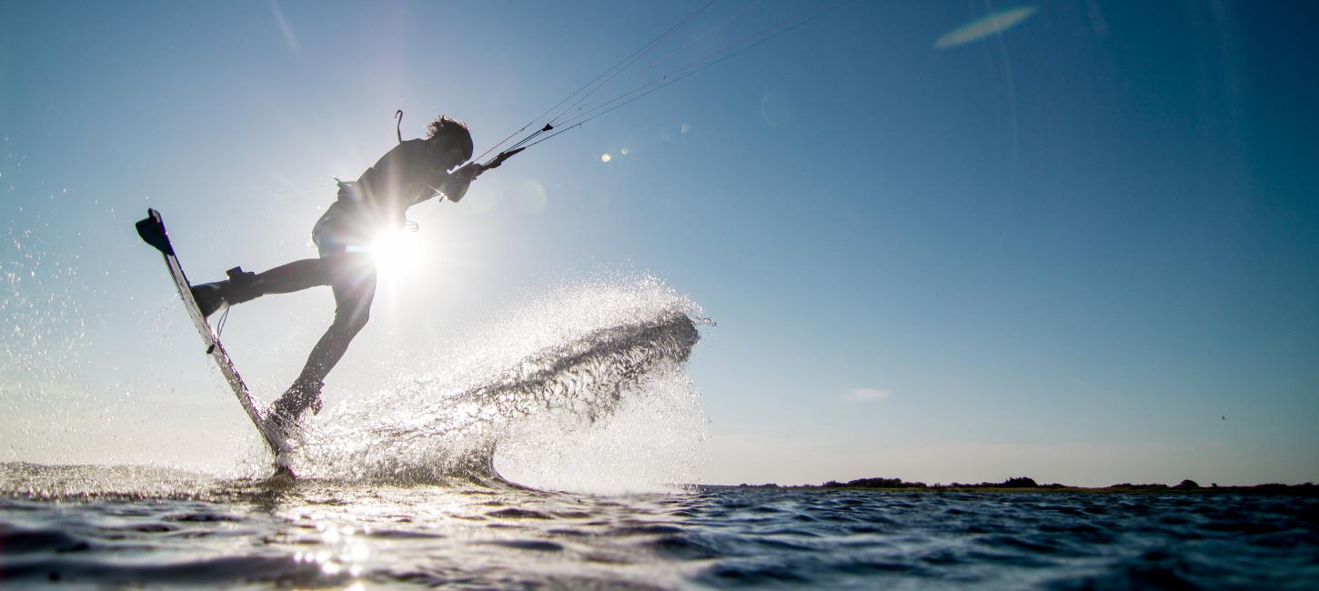 Mand kitesurfer over fjorden