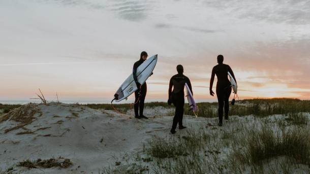 Surfers on a dune in sunset by the North Sea