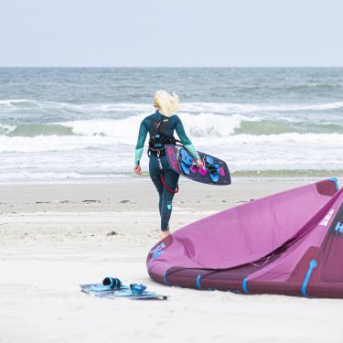 Kvinde på vej ud i vandet med hendes surfbræt