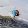 Surfer på en bølge med vindmøller i baggrunden